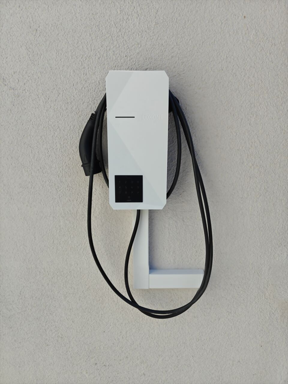 Fertig montierte Loxone Wallbox mit aufgehängtem Ladekabel an einer Hauswand in Blaufelden